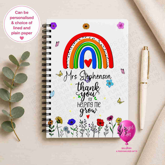 Personalised spiral-bound teacher notebook featuring a colourful rainbow, butterflies, wildflowers, and "Thank You for Helping Me Grow" wording, customised with the teacher's name and available with lined or plain pages.